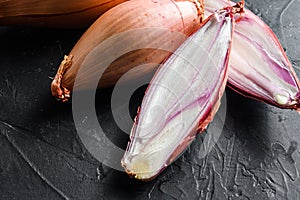 Shallot, eschalot or scallion raw ripe onions sliced and halved black background top view close up horisontal