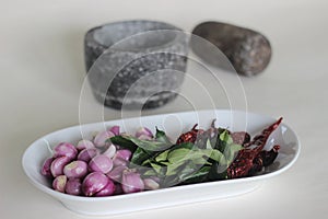 Shallots, curry leaves and red chillies ready to get pounded using Pestle and mortar