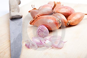 Shallots with old knife on wooden plate