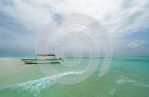 Shallow atoll sandbanks turquoise waves with lonely pleasure boat around Mnemba island in the Indian Ocean near the Zanzibar