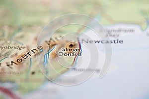 Shallow depth of field focus on geographical map location of Mount Slieve Donard in Northern Ireland Europe continent on atlas