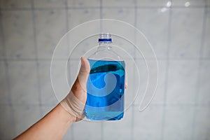 Shallow depth of field image selective focus with the hand of a man holding a plastic bottle of spirt - Romanian medical alcohol photo