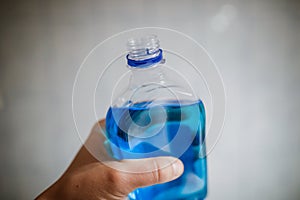 Shallow depth of field image selective focus with the hand of a man holding a plastic bottle of spirt - Romanian medical alcohol photo