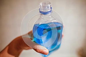 Shallow depth of field image selective focus with the hand of a man holding a plastic bottle of spirt - Romanian medical alcohol photo