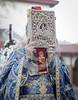 Shallow depth of field selective focus details with a Romanian orthodox christian priest holding a Holy Bible outside a church photo