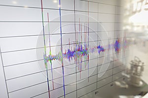 Shallow depth of field selective focus details with spikes on a seismogram on a digital display with the reflection of a device