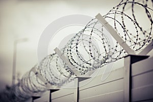 Shallow depth of field selective focus and filtered image with a razor wire on the outside wall of a governmental institution on