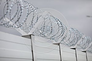 Shallow depth of field selective focus and filtered image with a razor wire on the outside wall of a governmental institution on