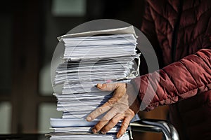 Shallow depth of field selective focus image with the hands of a man picking up a pile of files