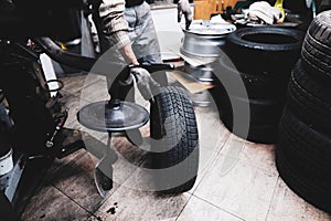 Shallow depth of field selective focus image with a mechanic changing the regular summer tyres of a car with winter tyres in a