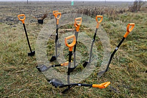 Shallow depth of field selective focus image with shovels during an autumn tree planting on a November cold and rainy day