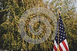 Shallow depth of field selective focus image with the US flag on a pole on a vegetal background