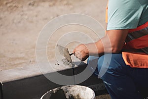 Shallow depth of field selective focus image with a worker cementing a sidewalk ledge on a construction site