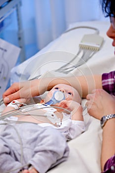 Shallow depth of field of sick infant boy undergoing a electrocardiography to check his heart.