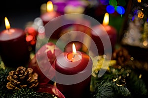 Shallow focus advent wreath with four lit candles and pine cones