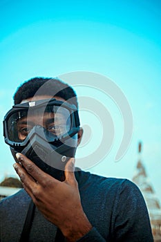 Shallow focus of a black person in a goggle mask against a blue background of sky