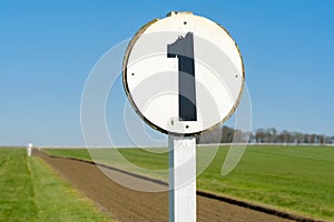 Shallow focus of a 1 furlong sign seen on a race horse training track.