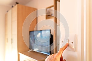 Shallow focus of a homeowner turning on a light switch in bedroom interior.