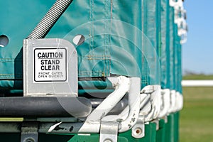 Shallow focus of horse racing turnstiles seen from the rear gates and caution sign.