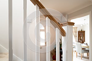 Shallow focus of a newly installed wooden banister seen near a porch and open dining room.