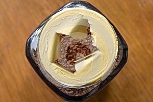 Shallow focus of a newly opened, instant coffee jar showing a tea spoon in the dried granules.