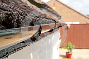 Shallow focus of newly painted black plastic guttering seen on a roof.