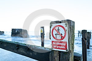 Shallow focus of a No Walking sign attached to old wooden and slippery gryones.