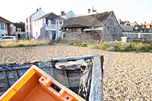 Shallow focus of an orange, plastic crate seen discarded in a on wooden boat.