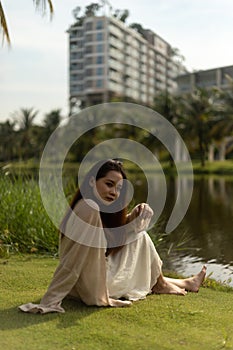 Shallow focus on a serious successful young Asian woman sitting on the grass at the park