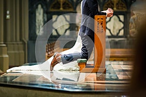 Shallow focus shot of a bride and groom kneeling on a prayer kneeler inside the church