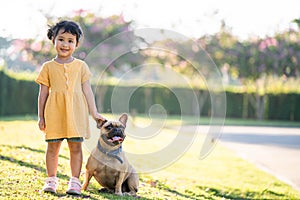Shallow focus shot of a cute southeast Asian girl with her french bulldog, in a park outdoors
