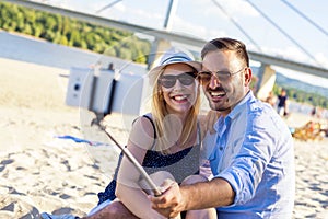 Shallow focus shot of a happy couple taking a selfie on a sandy beach