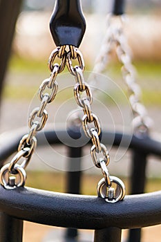 Shallow focus  shot of a silver metal chain attached to a kid's swing in a park