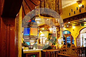 Shallow focus shot of small Arabic style lantern in blue, red and orange in a restaurant