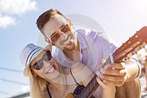 Shallow focus shot of a young Caucasian romantic couple playing the guitar in the beach