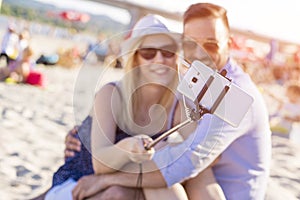 Shallow focus shot of a young Caucasian romantic couple taking a selfie in the beach