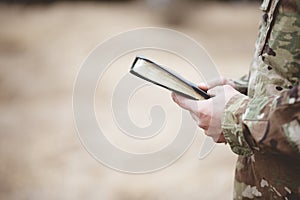 Shallow focus shot of a young soldier holding a bible in a field