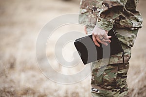 Shallow focus shot of a young soldier holding a bible in a field