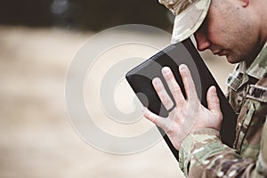 Shallow focus shot of a young soldier praying while holding the bible