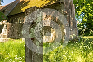Shallow focus, showing the stone texture of a crucifix shaped gravestone.