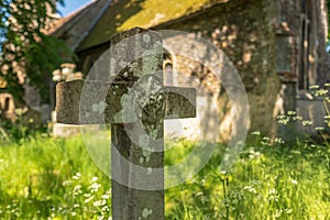 Shallow focus, showing the stone texture of a crucifix shaped gravestone.