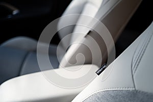 Shallow focus of an SRS Airbag tag seen attached to front part leather seats in a hybrid, new technology vehicle.