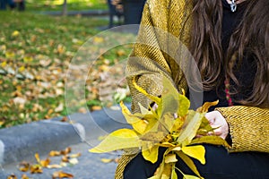 Shallow focus of a woman holding autumn leaves in a park