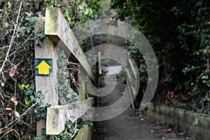 Shallow focus of a yellow footpath direction sign seen attached to a wooden bannister photo