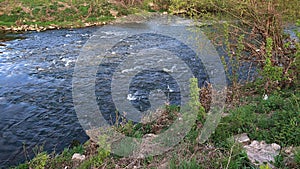 Shallow part or ford and crossing place on Nitra river with visible white foam and ripples above larger stones in water.