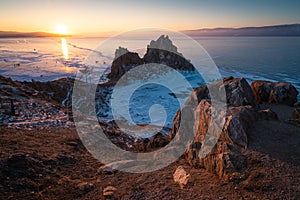 Shaman rock, sacred stone of Olkhon island, Baikal frozen lake in winter at beautiful sunset, Olkhon,Siberia, Russia