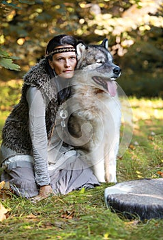 Shaman woman with an Alaskan Malamute dog in the forest