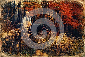 Shaman woman in autumn landscape with her horse. Old photo effect.