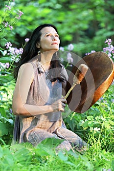 Shaman woman drumming among the flowers