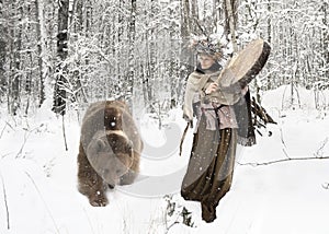 Shaman woman playing on shaman frame drum in a winter forest